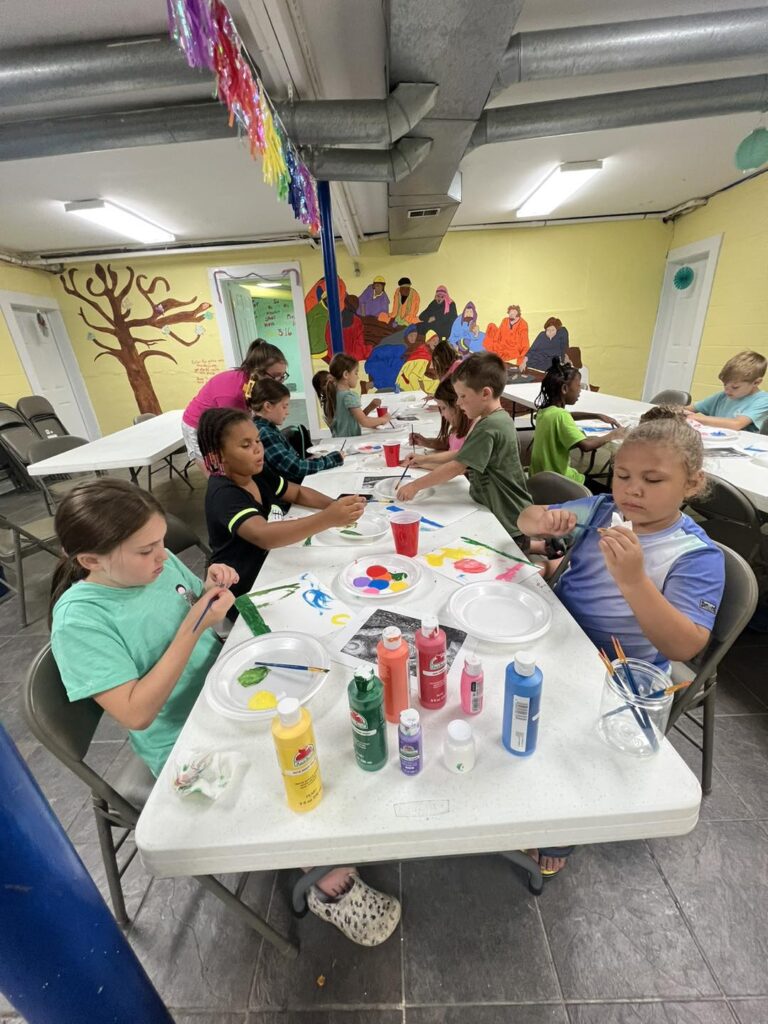 A group of children sitting at tables with paint.